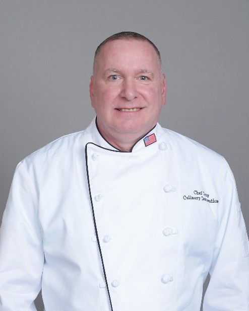 Male chef in white uniform with American flag.