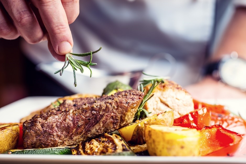 Rosemary garnish over grilled meat and vegetables.