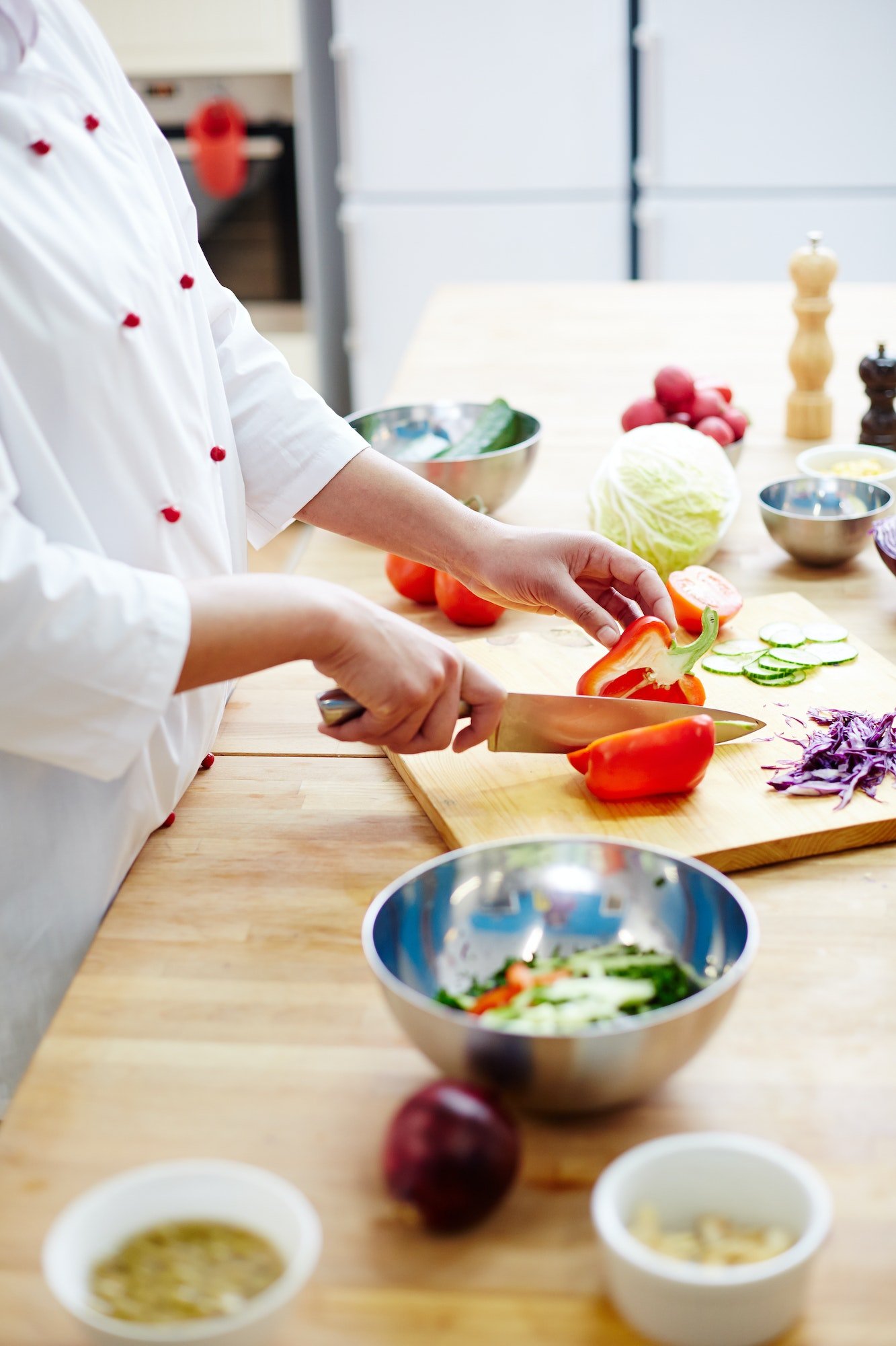 Chef slicing red peppers on cutting board.