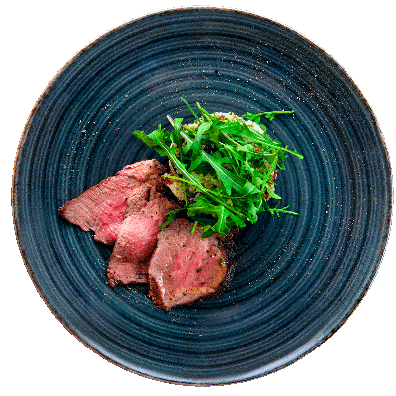 Sliced beef with arugula salad on a plate.