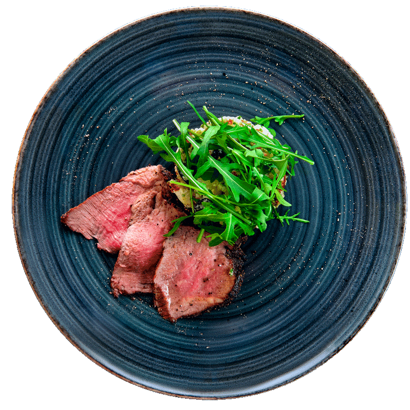 Sliced steak with arugula on blue plate.